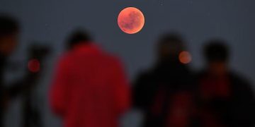 Хората се събират, за да гледат „кърваво лунно“ затъмнение в Мелбърн, Австралия, на 28 юли 2018 г. На 13-14 март 2025 г. наблюдателите на небето в цяла Северна Америка ще имат страхотна гледка, докато Луната става червена по време на пълно лунно затъмнение – първото видимо в региона от 2022 г. насам. © Уилям Уест, AFP/Getty Images