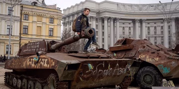 Момче седи на повреден руски танк в центъра на Киев, Украйна. Март 2025 г. Авторско право AP