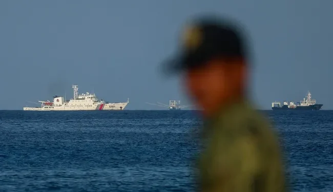 Филипински морски пехотинец наблюдава кораби на китайската брегова охрана край бреговете на остров Титу в контролираните от Манила спорни води в Южнокитайско море. 3 май 2026 г. Daniel Ceng / Anadolu / Getty